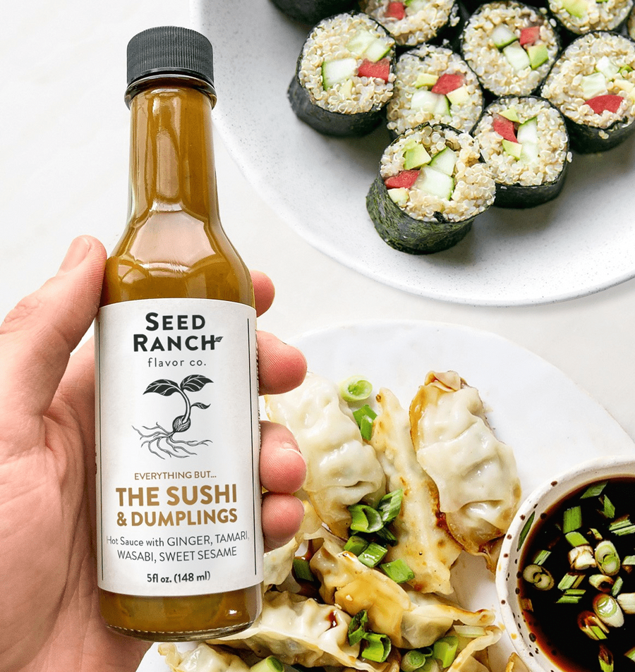 Hand holding a bottle of Seed Ranch sauce with sushi and dumplings in the background